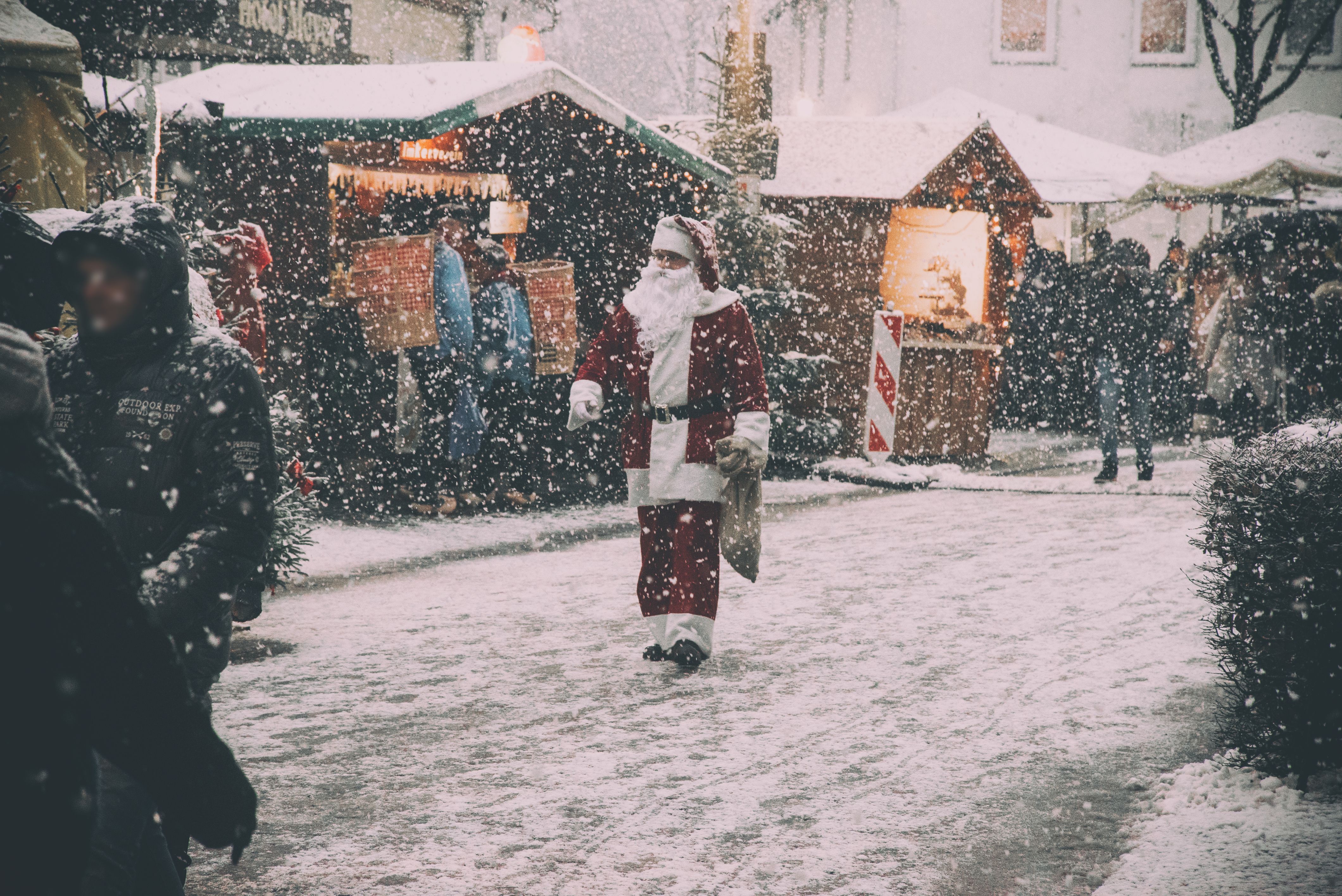 Adventzauber Borgholzhausener Weihnachtsmarkt im Schnee mit Weihnachtsmann und beleuchteten Holzhütten.
