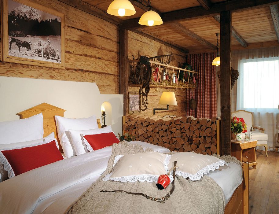 Gemütliches Hotelzimmer im alpinen Stil mit Holzwänden, einem großen Bett und rustikaler Dekoration.