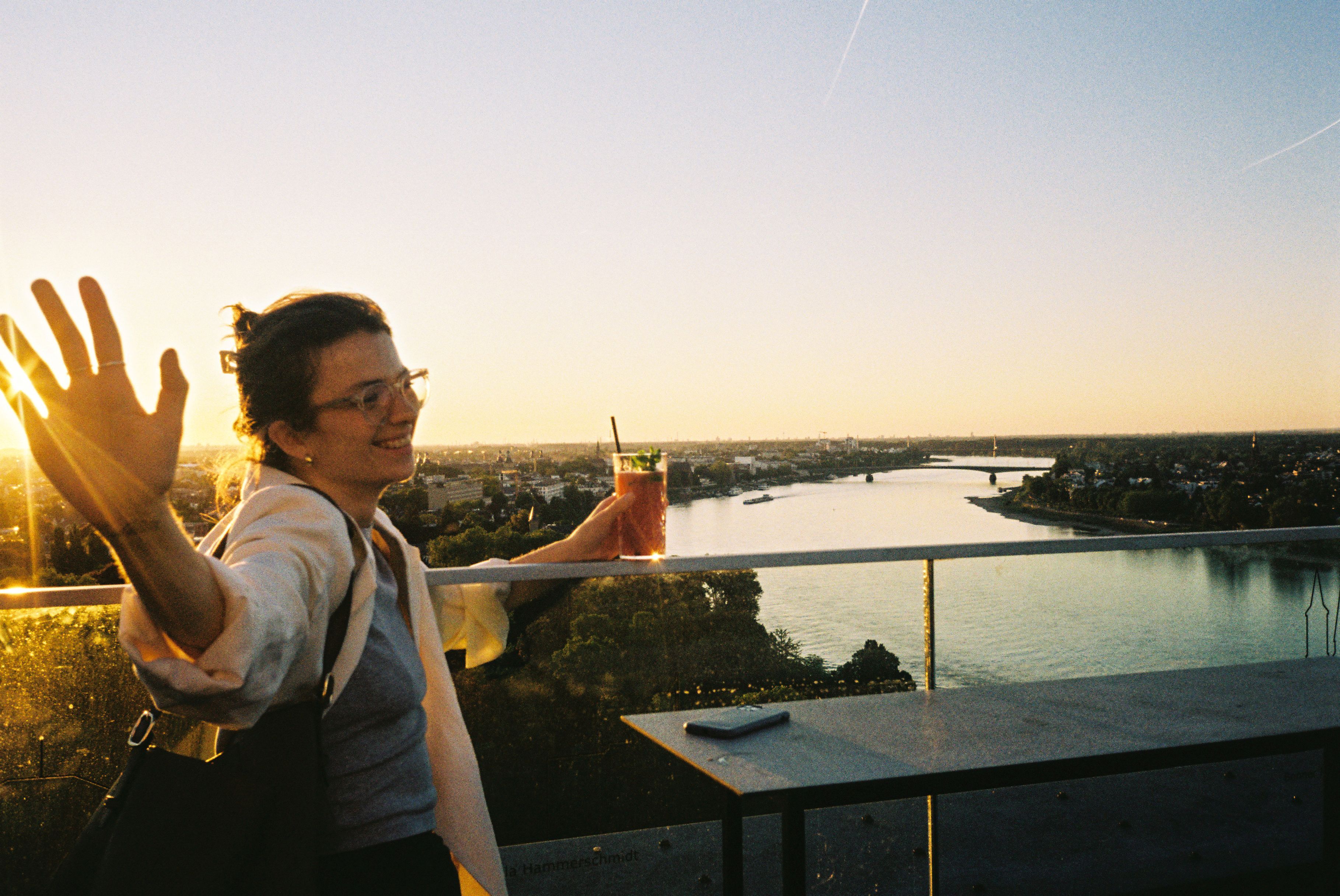 Molle & Korn, Henri Schade, Frau mit Getränk steht auf der Marriott Hotel Rooftop Bar in Bonn.