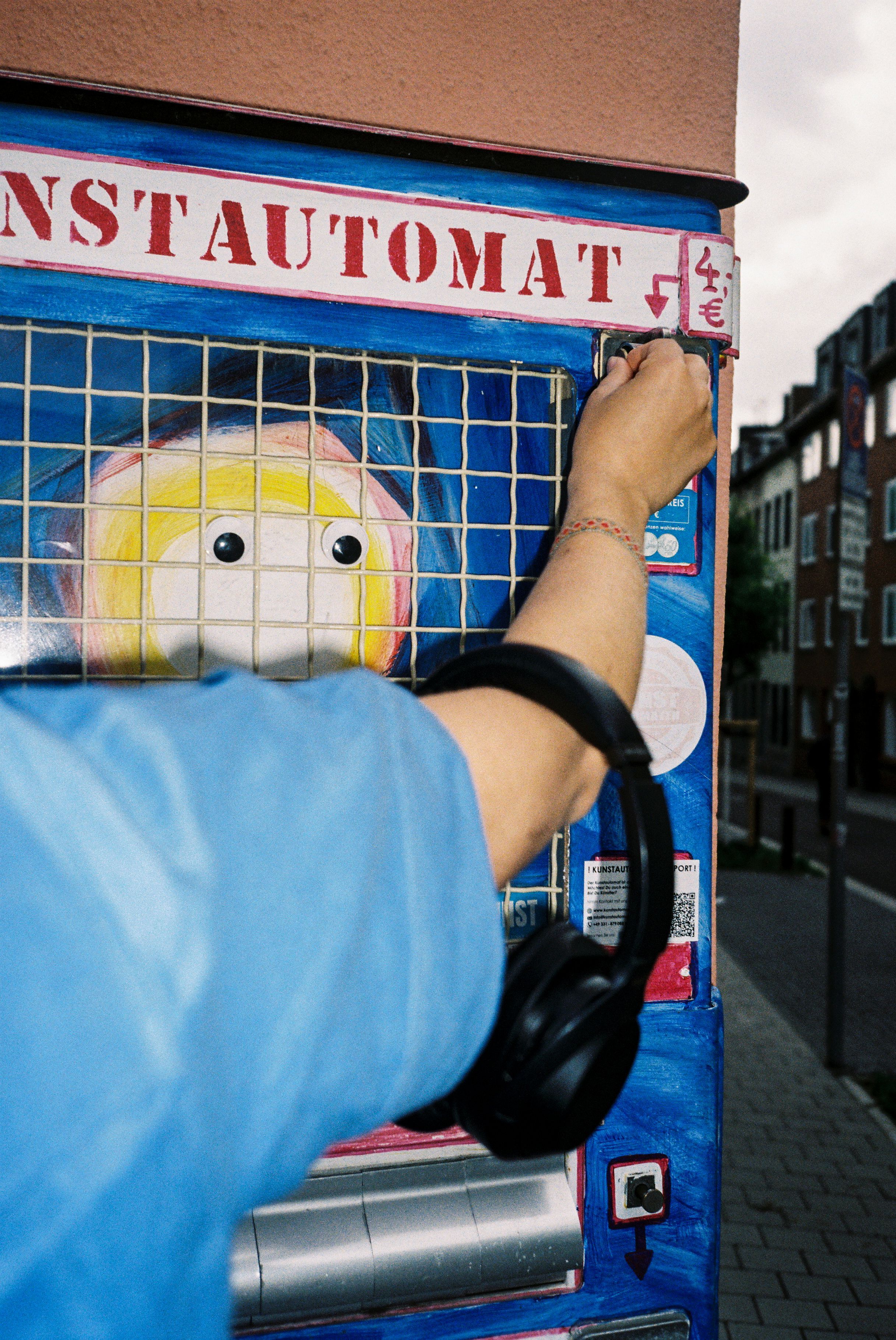Arm vor einem künstlerisch gestalteten Automaten in Aachen.