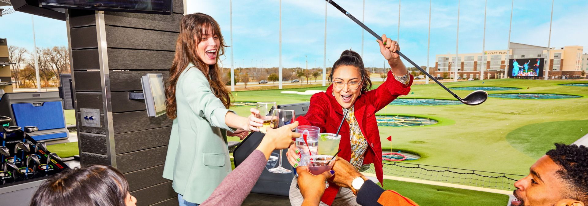 Menschen stoßen mit Getränken an einem Golfplatz an.