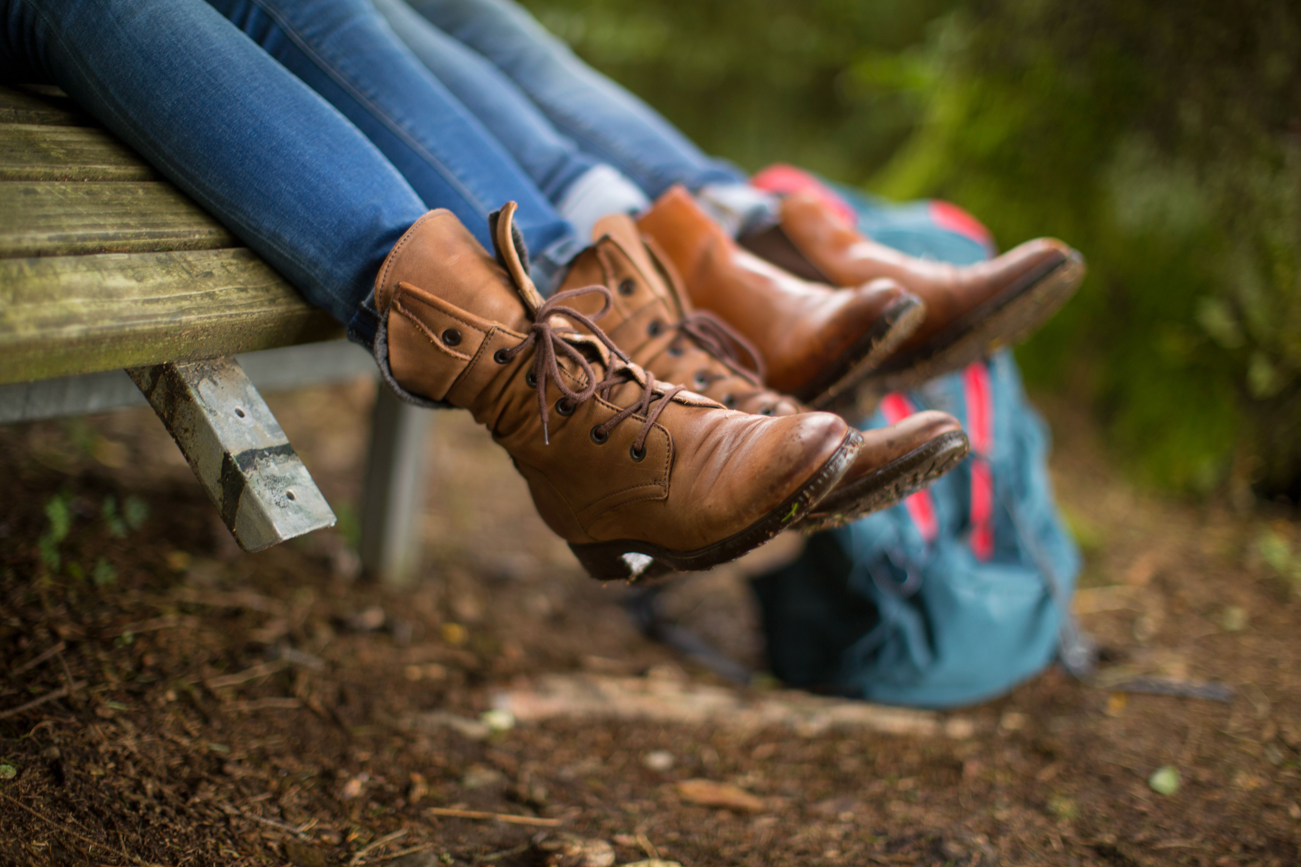 Zwei Personen mit Wanderschuhen sitzen auf einer Bank im Wald.