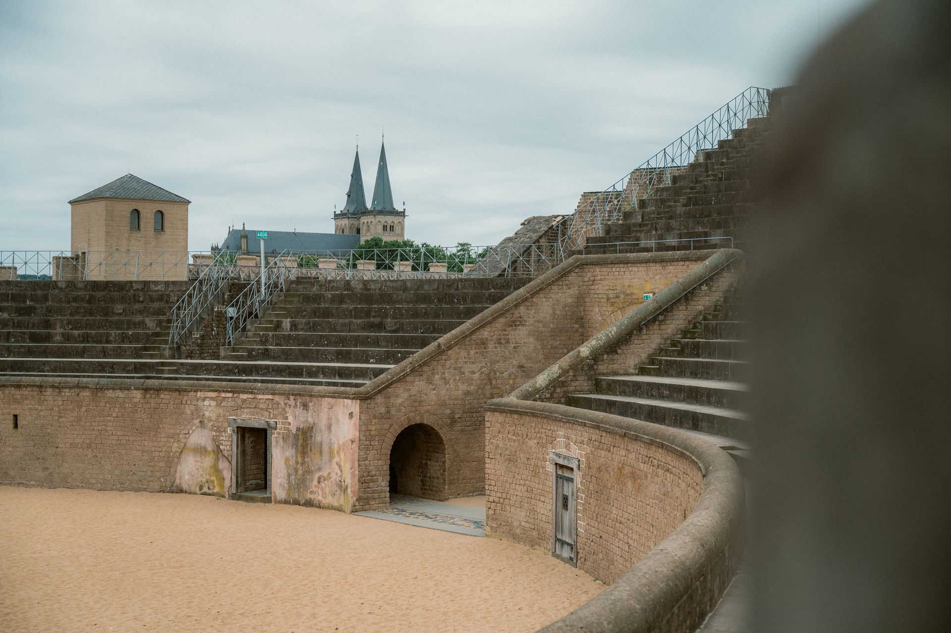 Amphitheater im LVR-Archäologischen Park Xanten mit Kirchtürmen im Hintergrund.