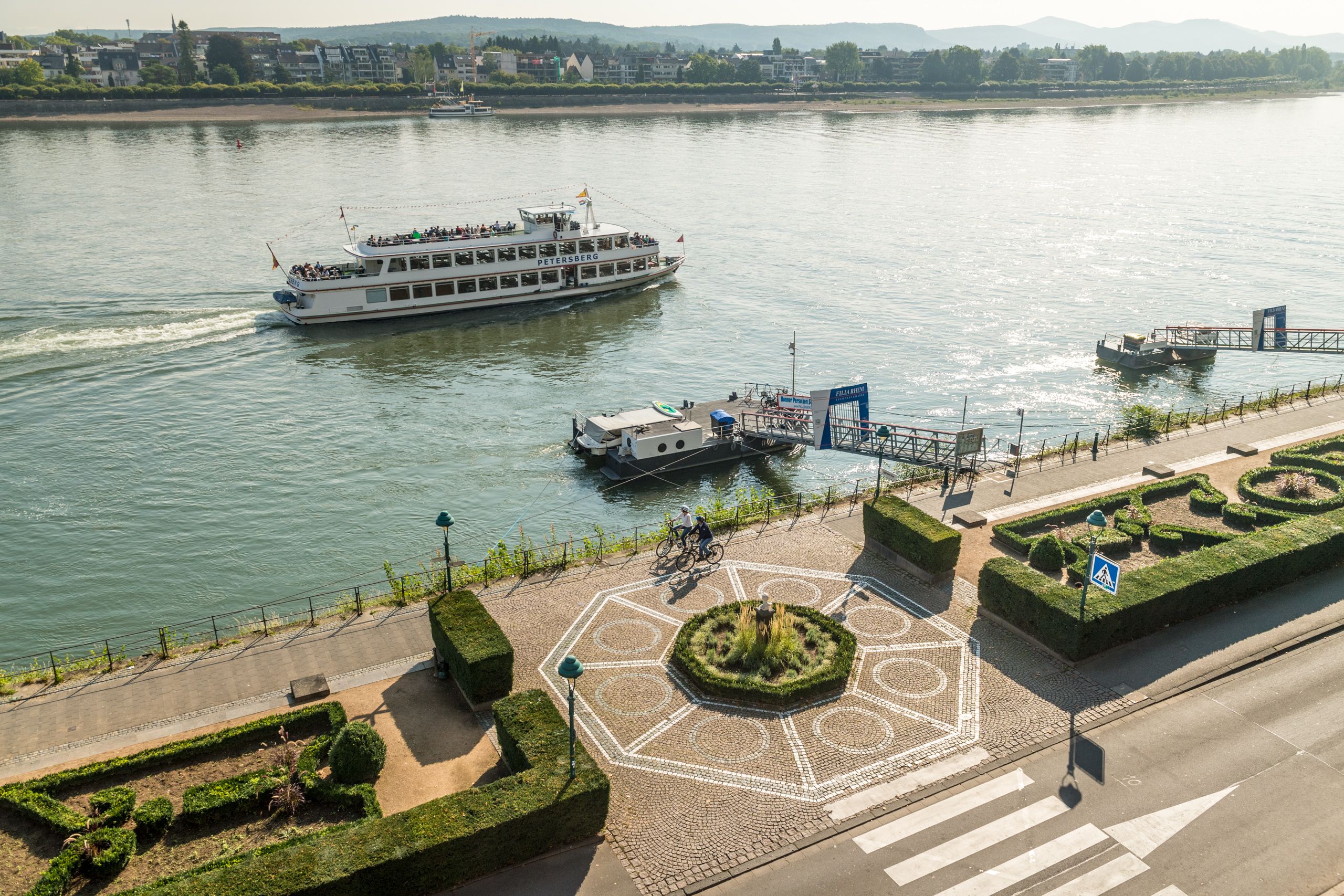 Zwei Radfahrer fahren am Rhein entlang.