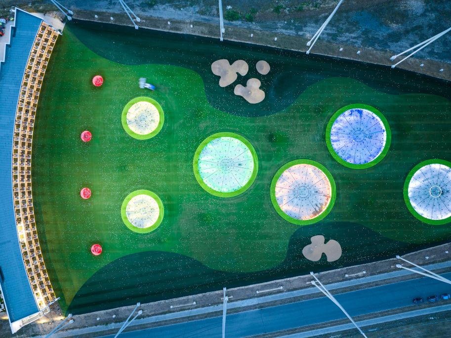 Luftaufnahme eines Topgolf-Feldes mit beleuchteten Zielen und Abschlagplätzen.