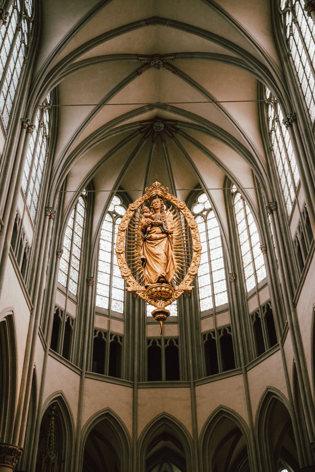 Die goldene Maria-Skulptur schwebt im Altenberger Dom, umgeben von gotischen Fenstern und hohen Gewölben.