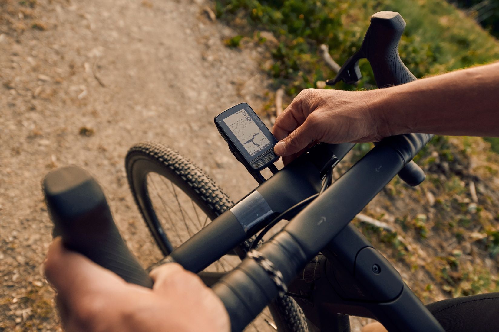Nahaufnahme eines Gravelbikes mit Navigationsgerät auf einem Schotterweg.