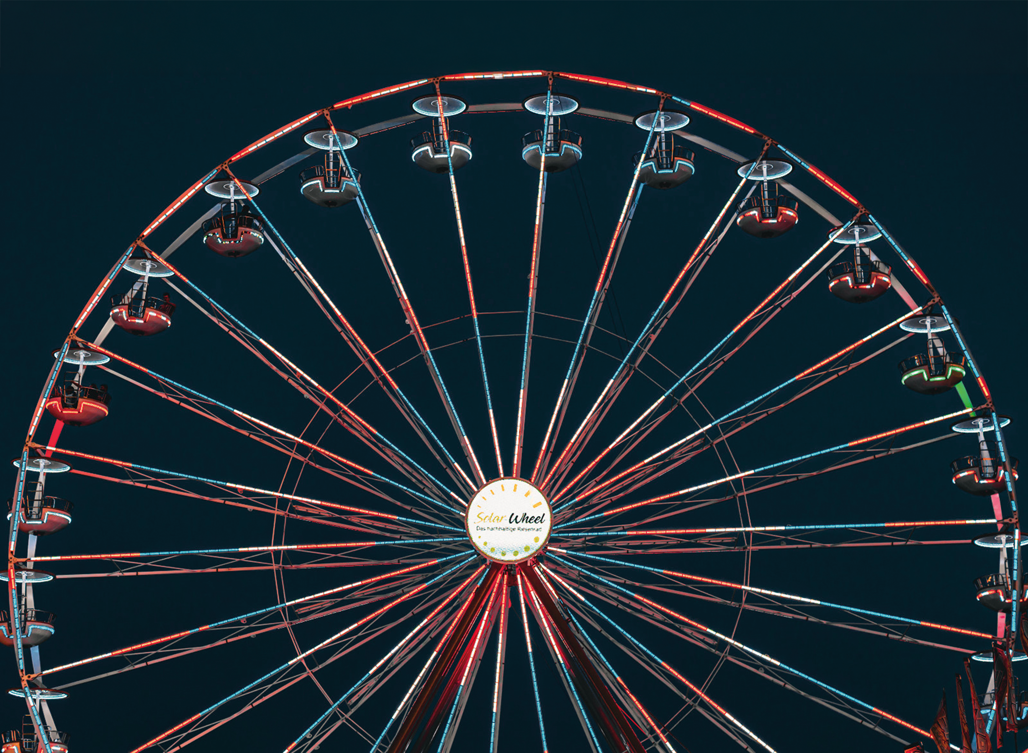 Leuchtendes Riesenrad „Solar Wheel“ bei Nacht mit roten und blauen LED-Lichtern vor dunklem Himmel.