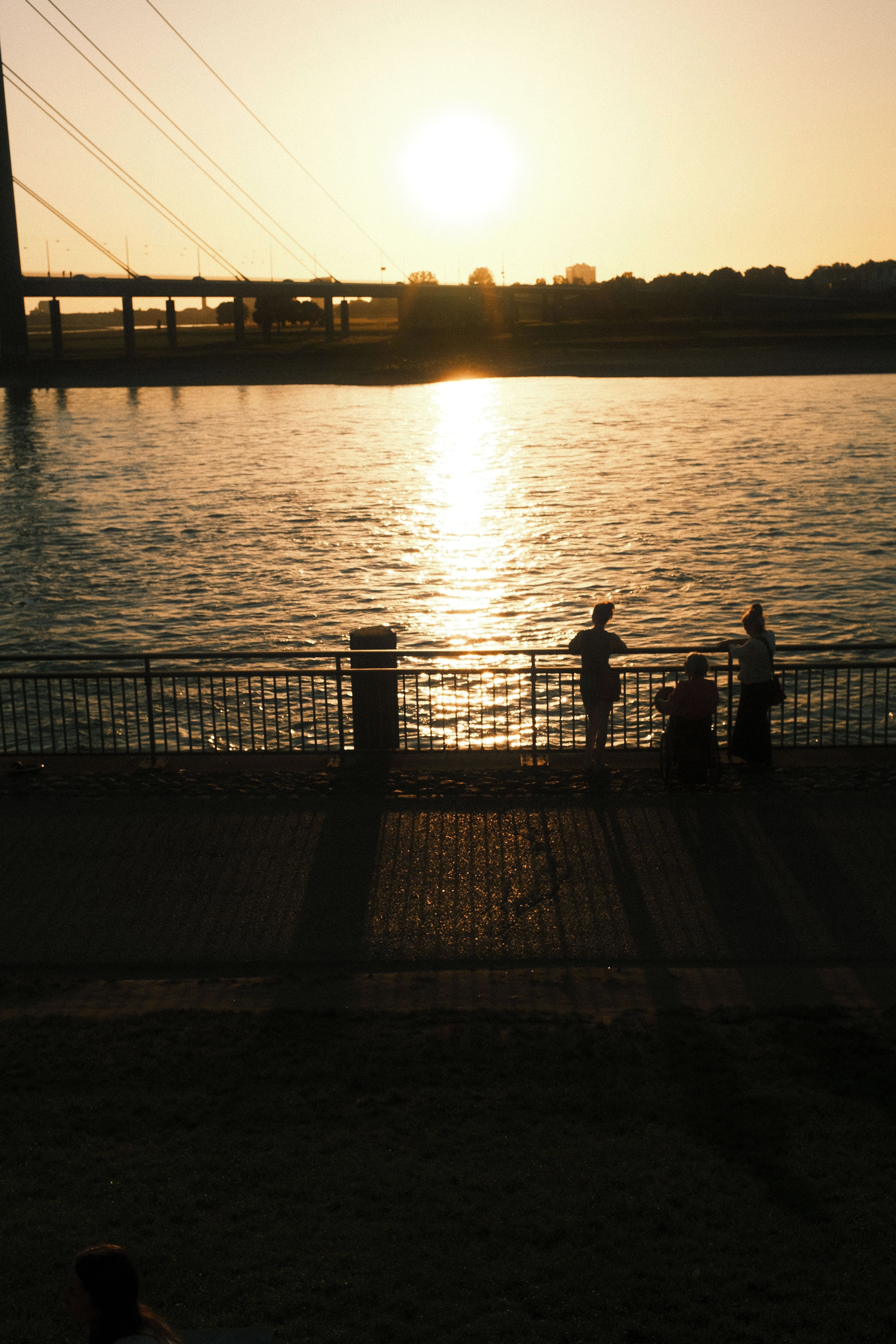 Menschen blicken auf den Sonnenuntergang an der Rheinuferpromenade in Düsseldorf.