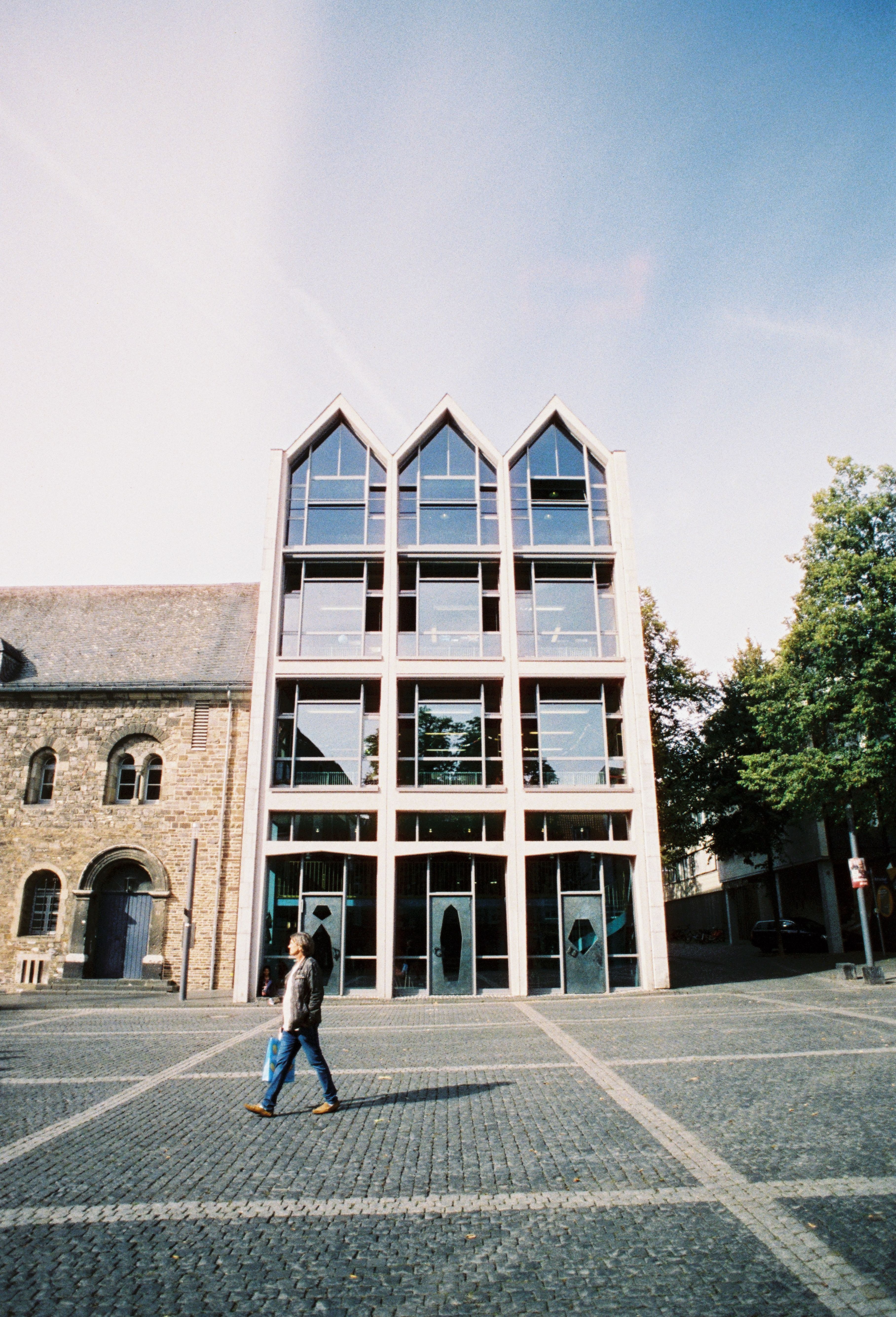 Ein modernes Gebäude mit Glasfassade neben einem alten Steinbau in der Aachener Altstadt.