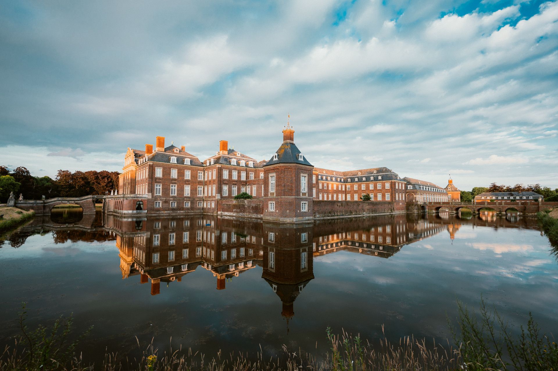 Schloss und Wolken-Himmel spiegeln sich im Wasser  