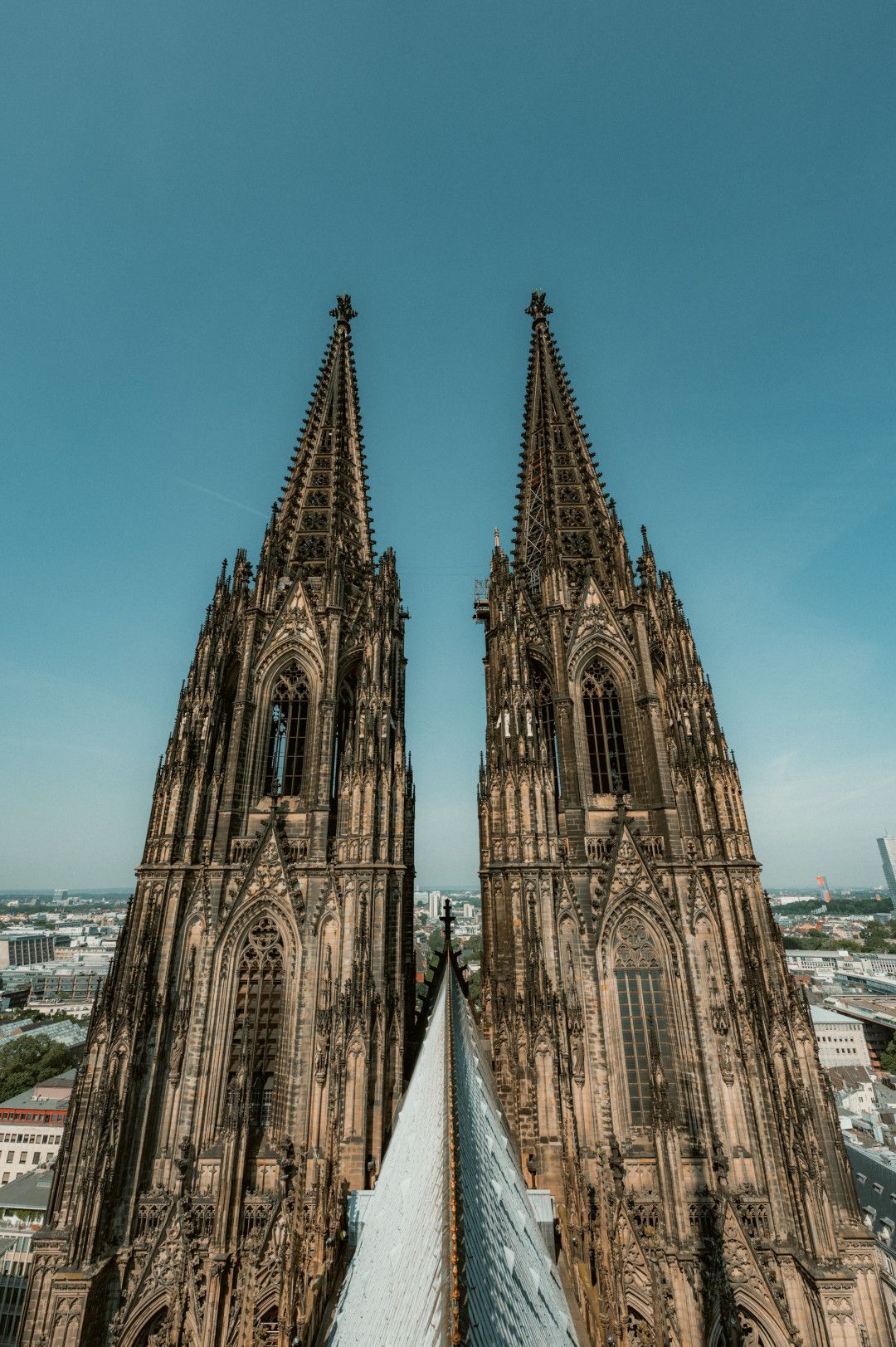 Die imposanten Türme des Kölner Doms ragen in den blauen Himmel. Die gotische Architektur ist detailliert und beeindruckend.