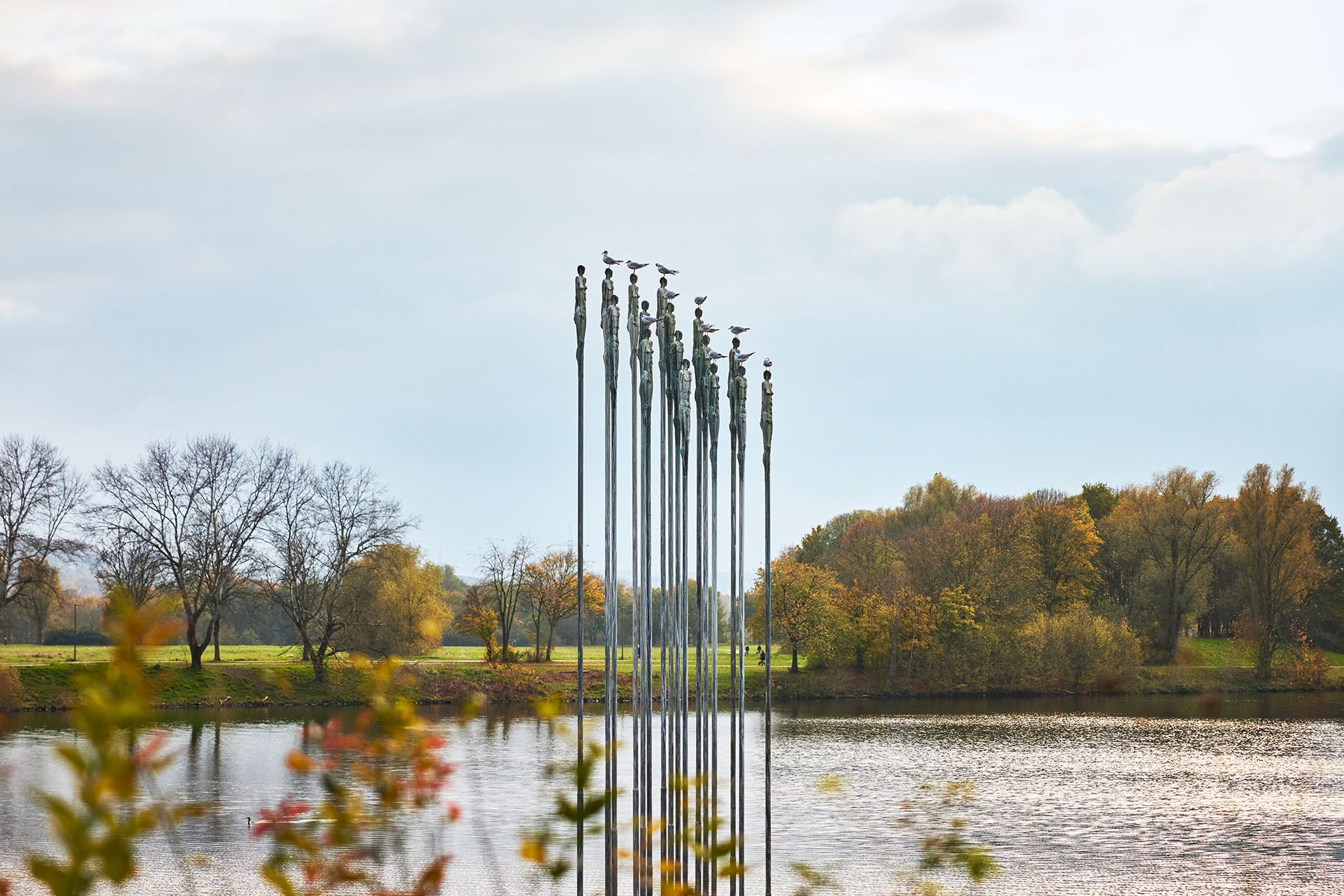 Skulpturen am Kemnader See in Witten mit Vögeln darauf, umgeben von herbstlichen Bäumen.