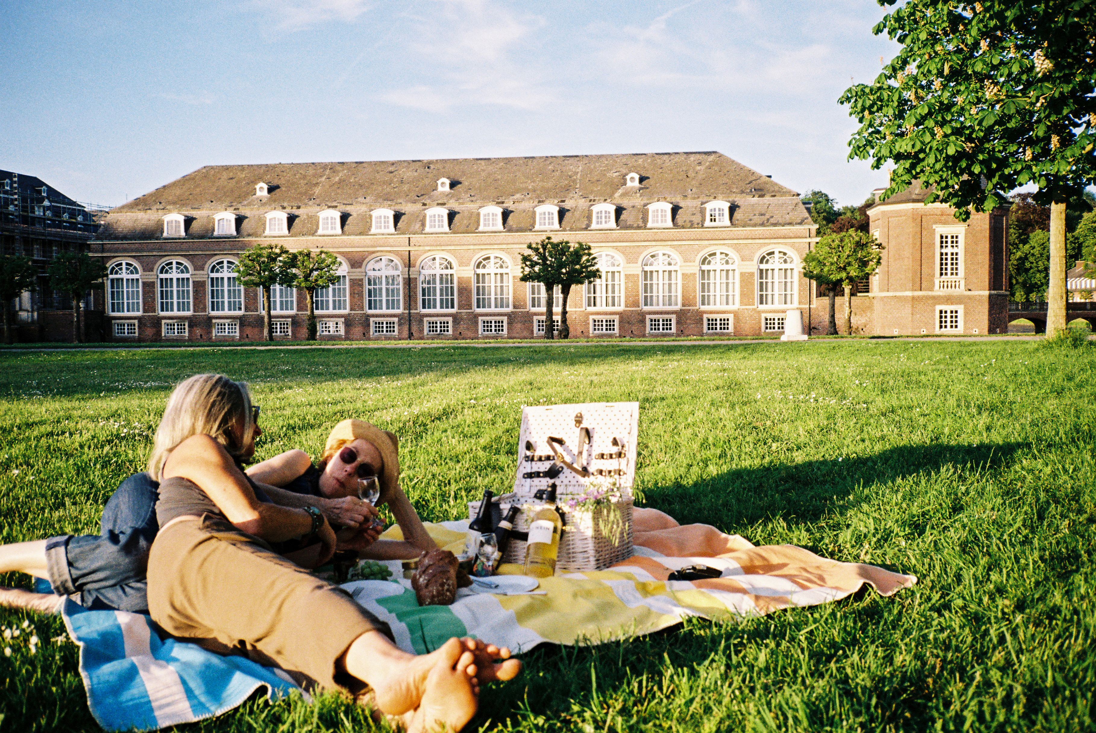 Zwei Frauen beim picknicken auf einer Wiese bei Schloss Nordkirchen im Münsterland.