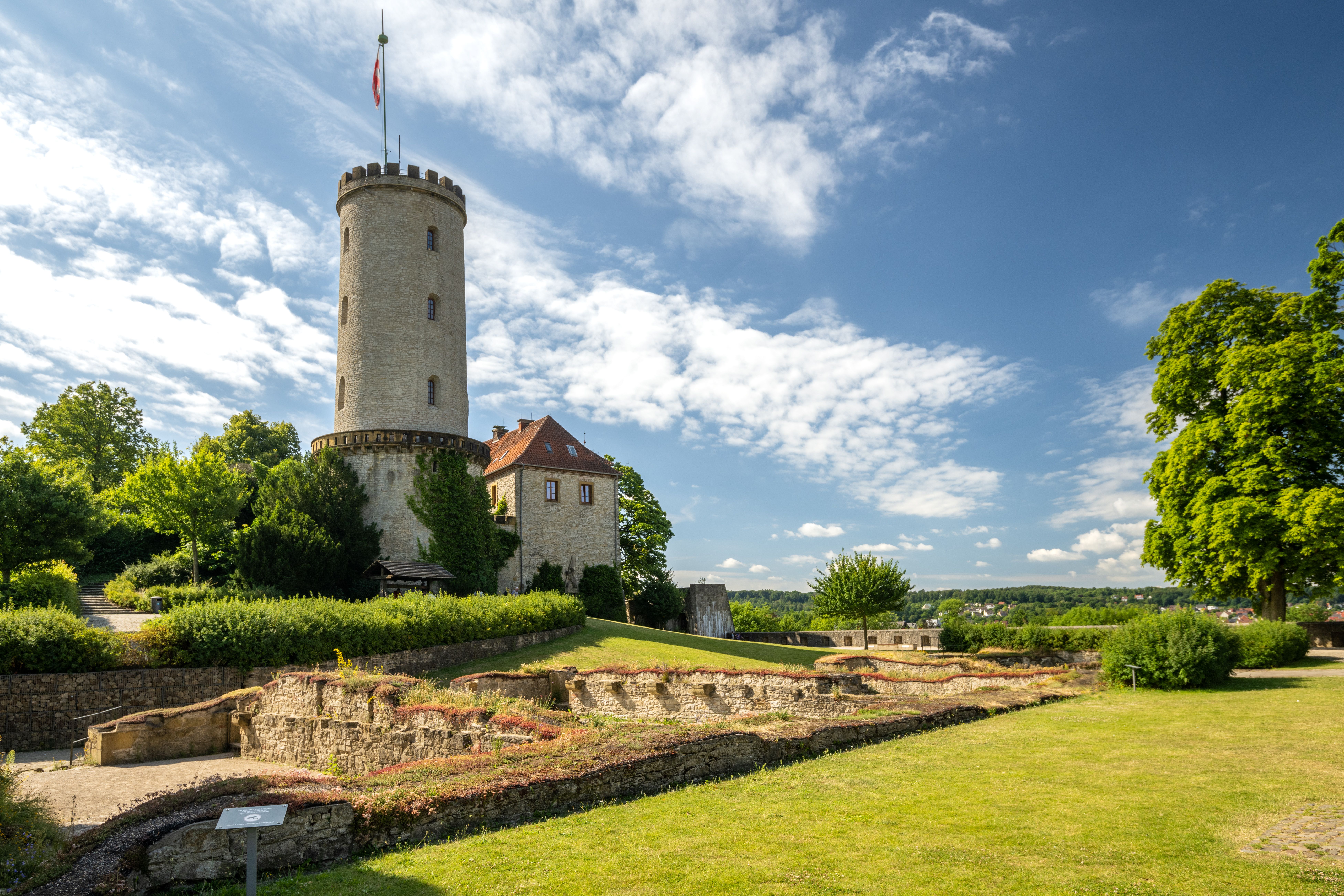 Die Sparrenburg in Bielefeld mit einem runden Turm und grüner Umgebung bei sonnigem Wetter.