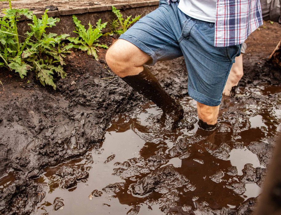 Person watet durch schlammiges Wasser in einem Moortretbecken.