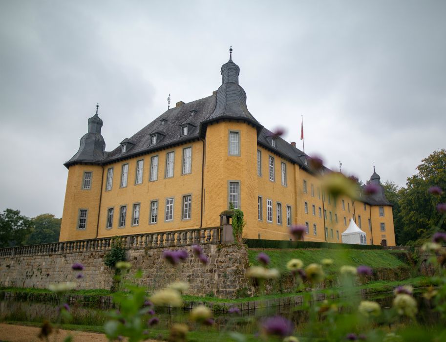 Schloss in gelb. im Vordergrund Blumen