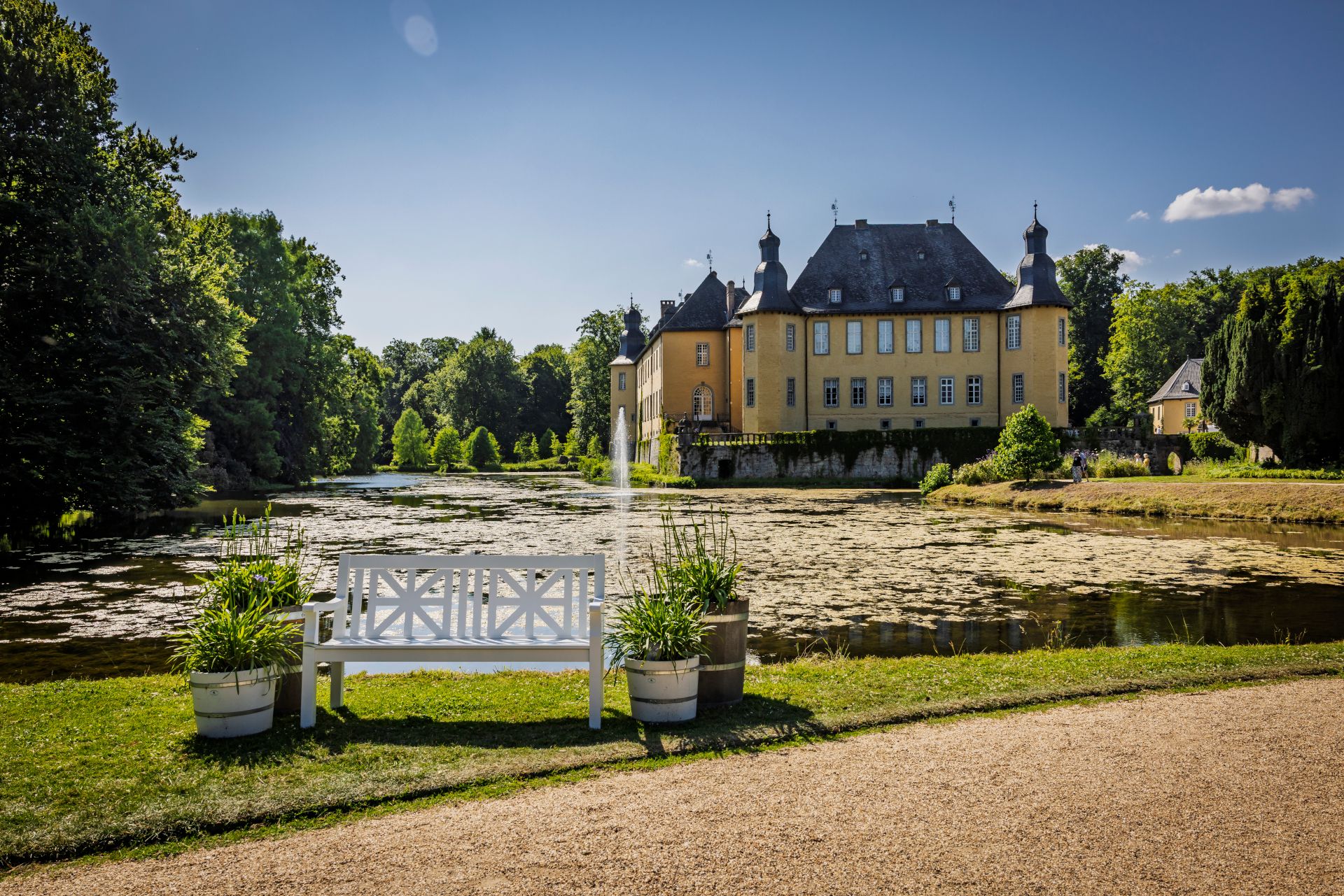 Rund um den Teich des Schlosses Dyck können Gäste die wunderbare Aussicht auf Bänken genießen. Das Wasserschloss in Jüchen ist ein Blickfang