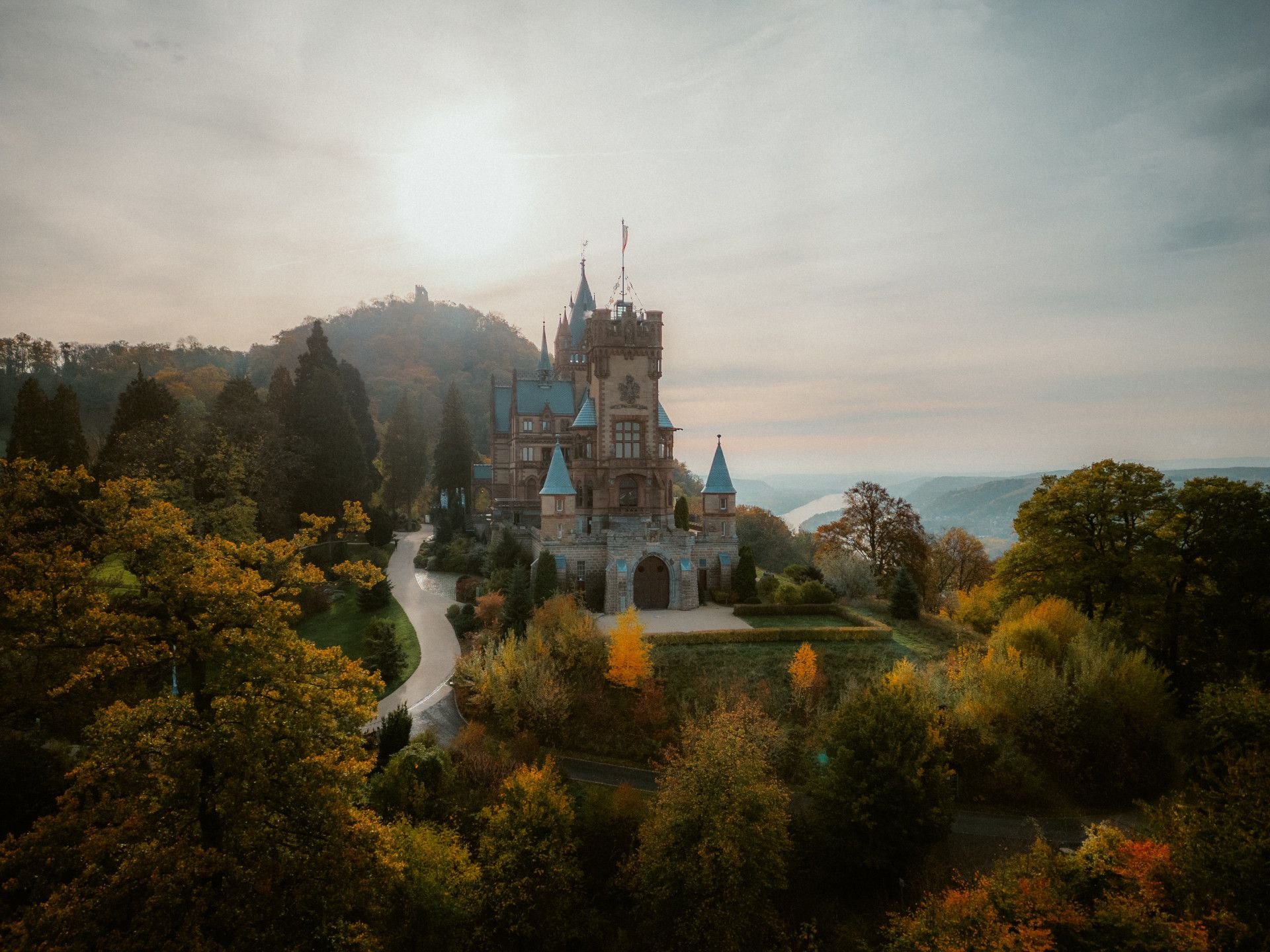 Schloss Drachenburg in herbstlicher Landschaft bei Sonnenuntergang.