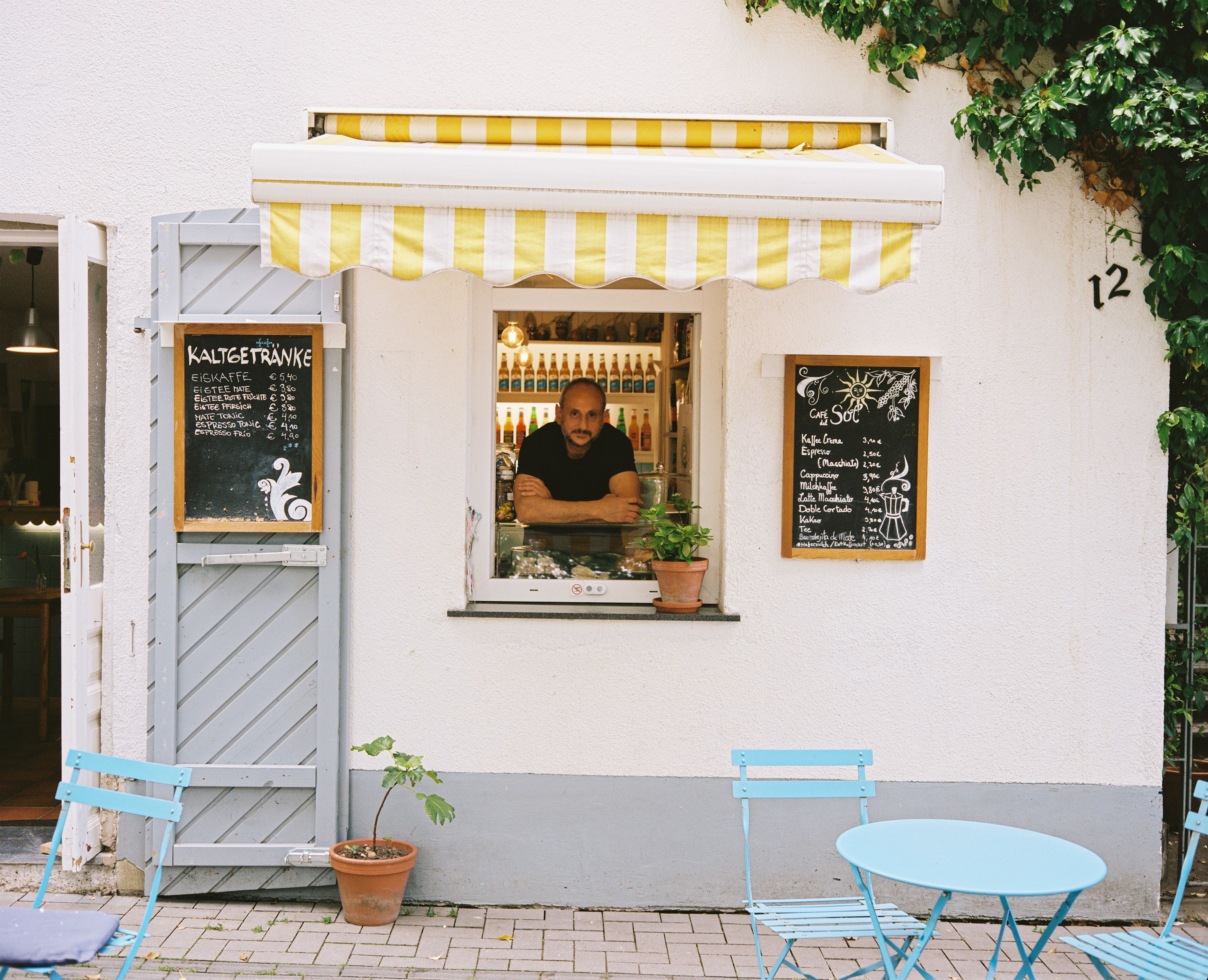 Ein Ladebesitzer eines Kiosk schaut aus seinem Verkaufsfenster heraus in Aachen.