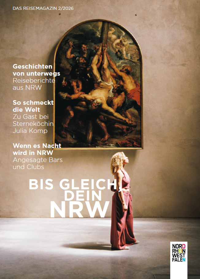 Frau steht vor einem großen Gemälde und schaut hoch ins Licht, das durch ein Fenster in den Ausstellungsraum fällt.