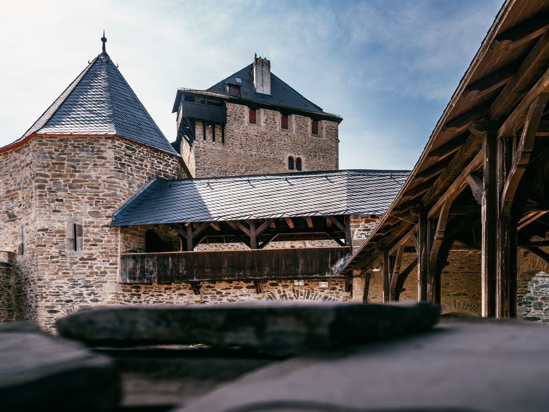 Blick auf die Nordterrasse einer historischen Burg mit steinernen Mauern und Schieferdächern.