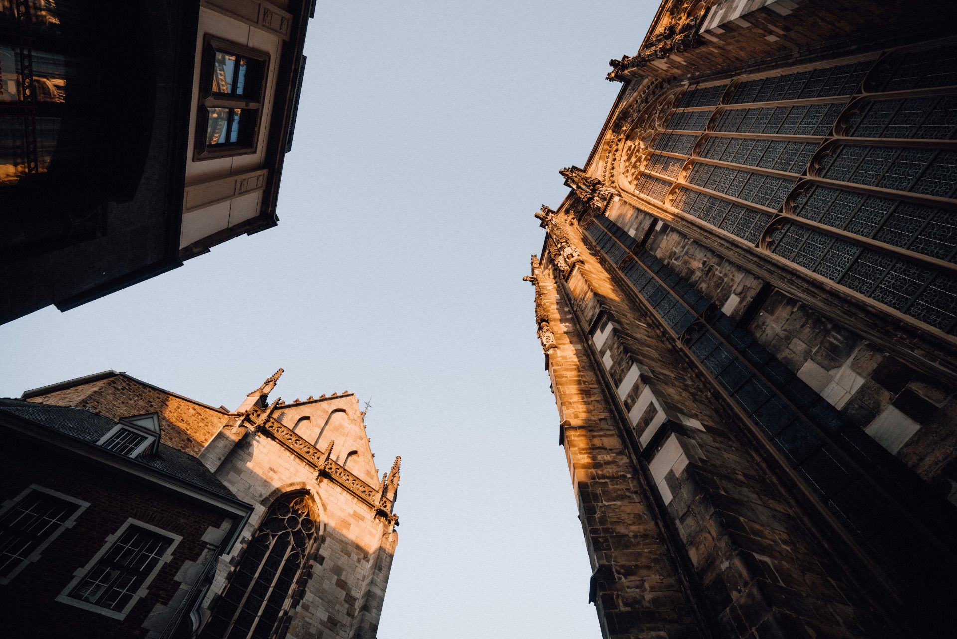 Blick von unten auf den Aachener Dom mit gotischen Fenstern und Architektur im Sonnenlicht.