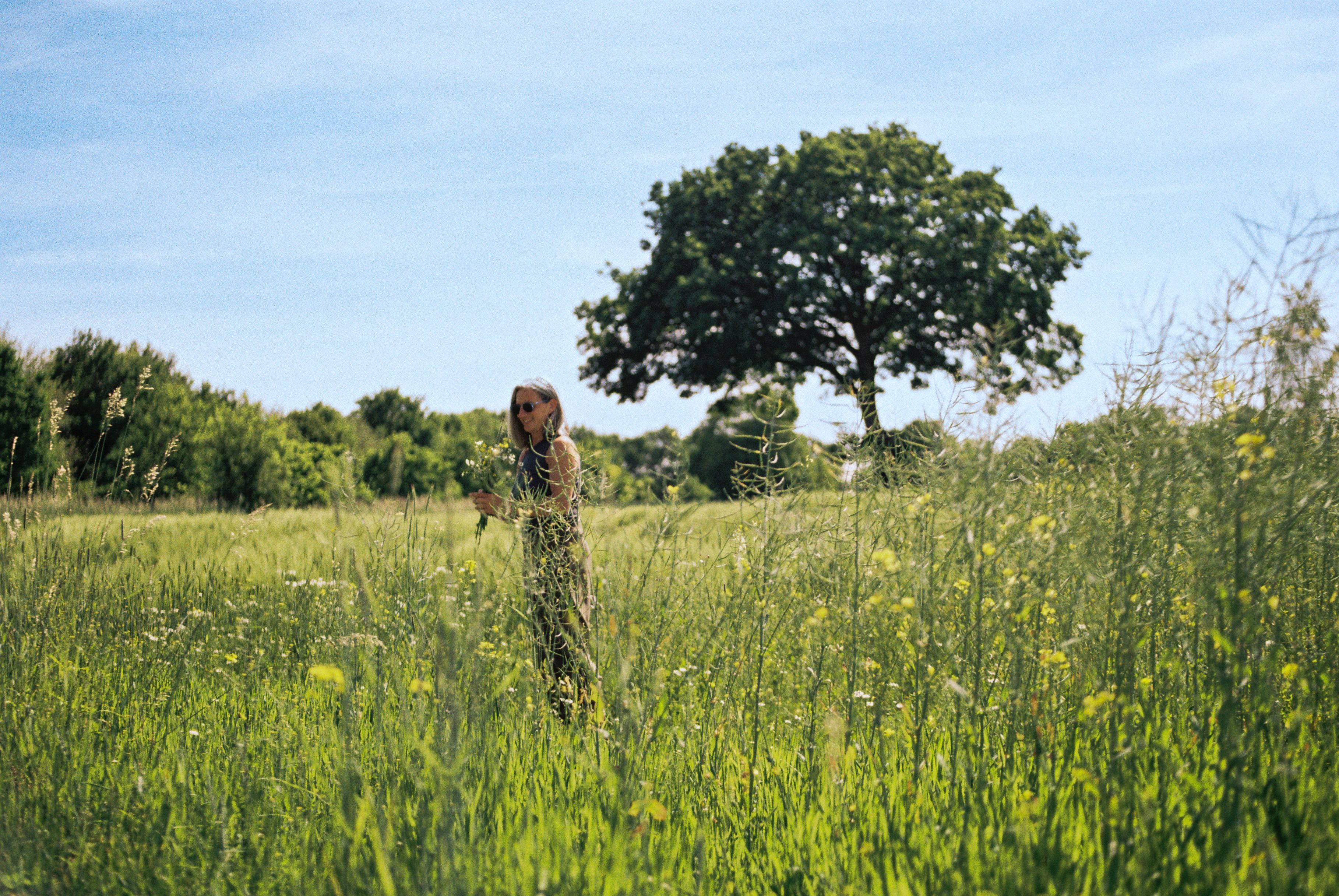 Frau steht auf einer Wildblumenwiese im Münsterland mit einem Blumenstrauß in den Händen.