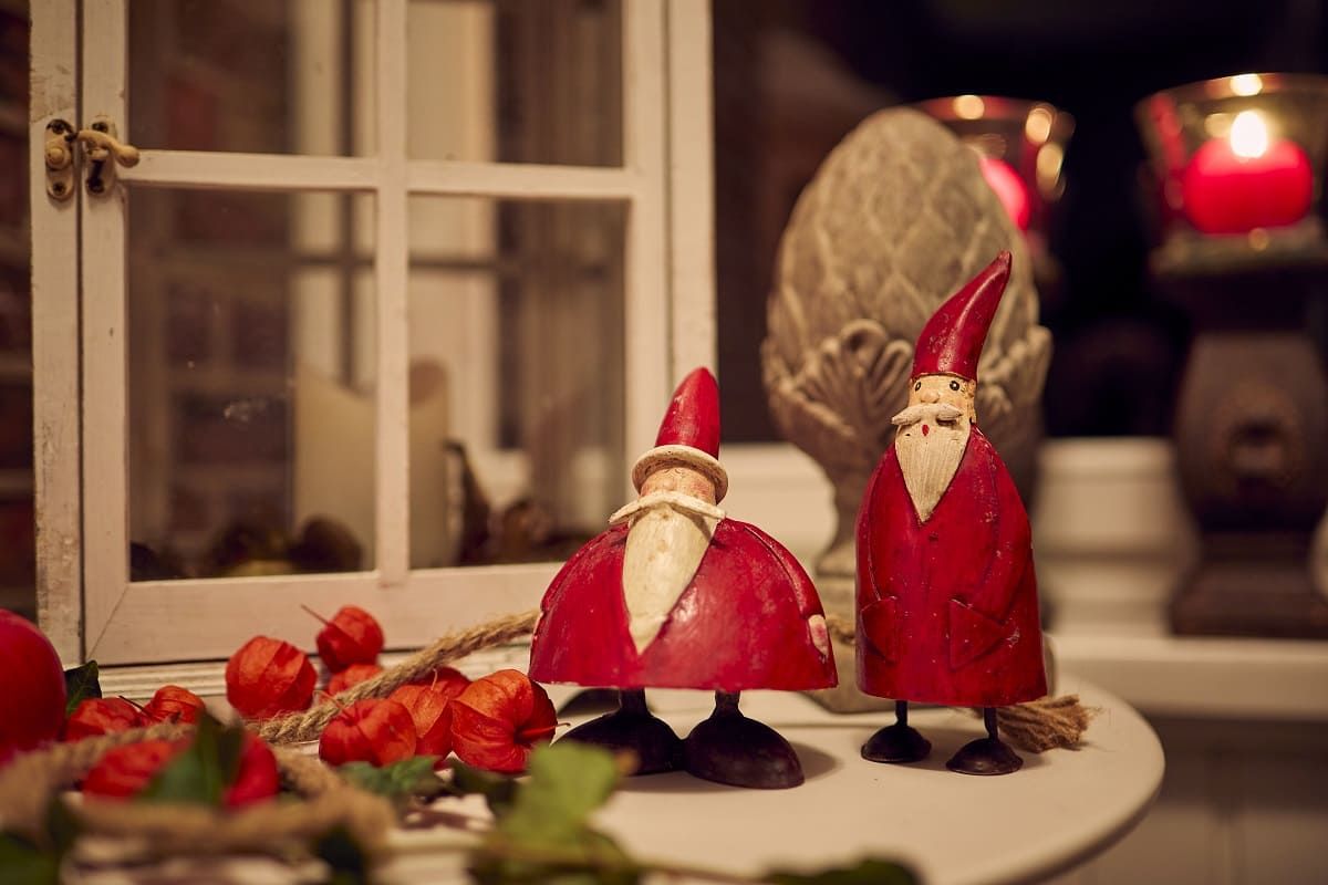 Zwei rote Nikolausfiguren aus Holz stehen auf einem Tisch.