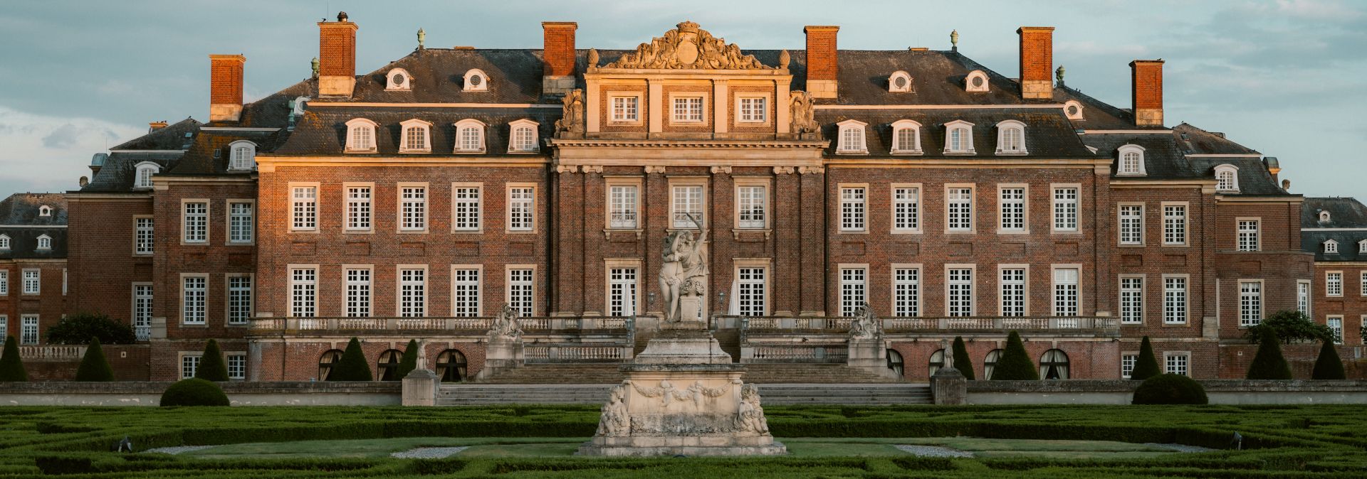Schloss mit Park und Statue im Abendlicht