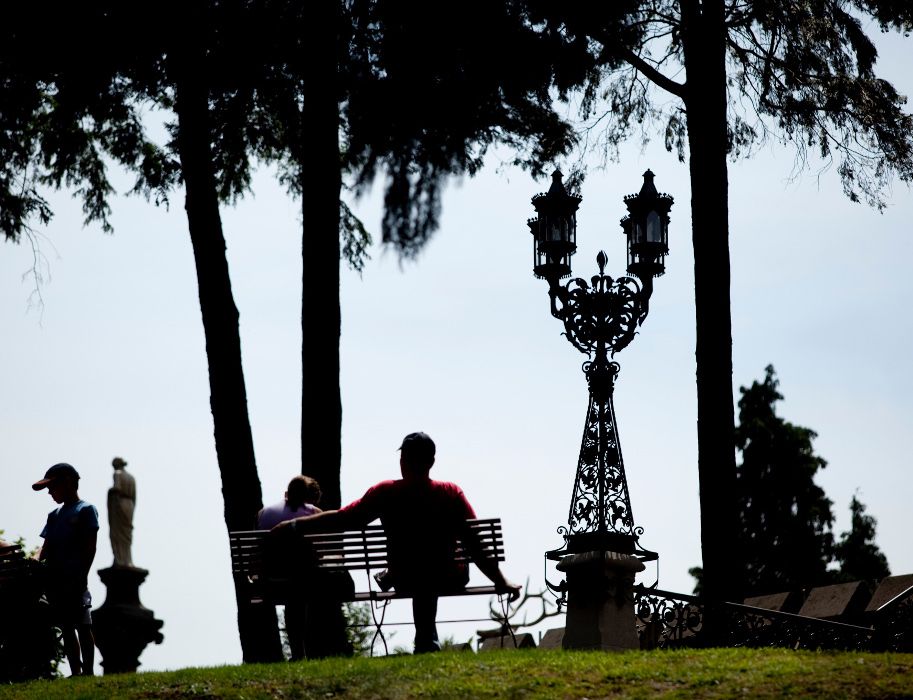 Silhouette von Menschen auf einer Parkbank im Schlosspark mit Laterne und Bäumen im Hintergrund.