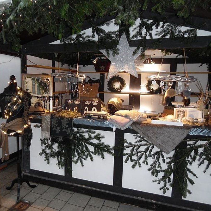 Ein festlich dekorierter Weihnachtsmarktstand mit Schmuck, Schals und Dekorationen.
