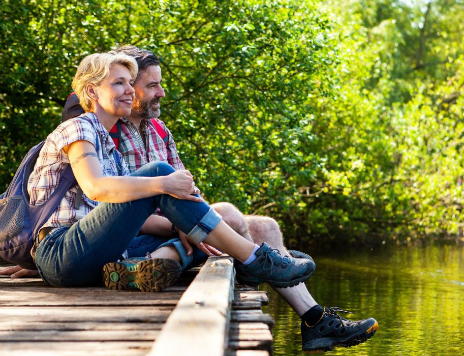 Ein Paar sitzt auf einem Holzsteg am Glabbacher Bruch, umgeben von grüner Natur.