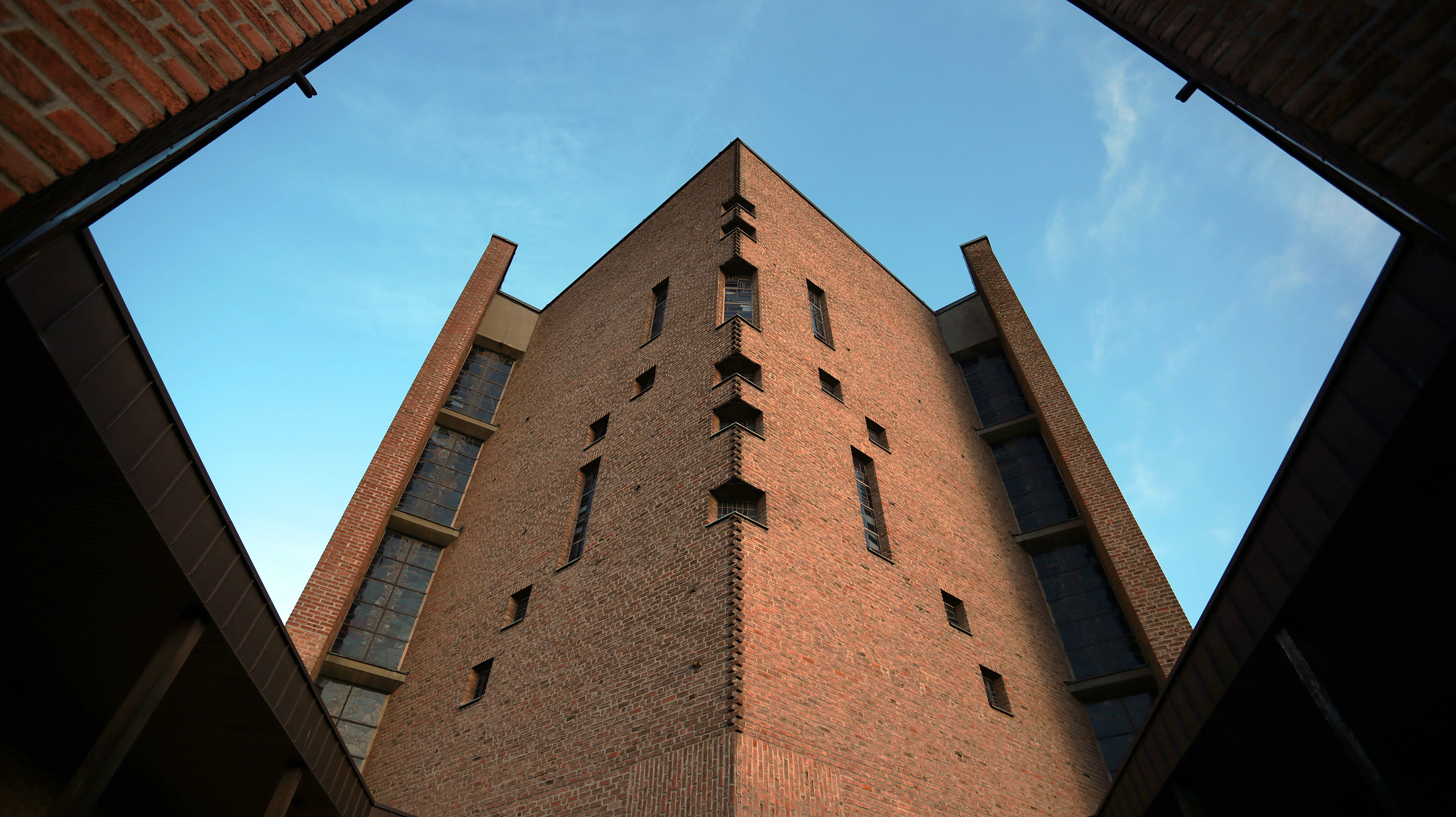 Die Abtei Königsmünster im Sauerland erhebt sich mit ihrer markanten Backsteinarchitektur aus der Froschperspektive in den Himmel. Klare Linien, schmale Fenster und die schlichte, monumentale Bauweise prägen das Erscheinungsbild des Klosters.