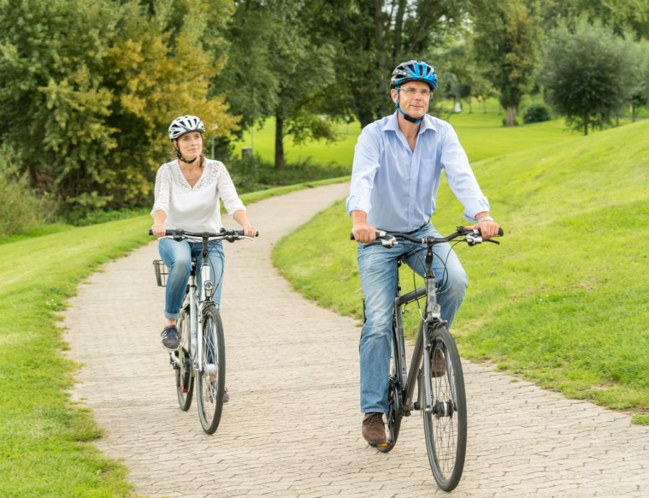 Zwei Radfahrer auf einem Weg im Grünen, beide tragen Helme.