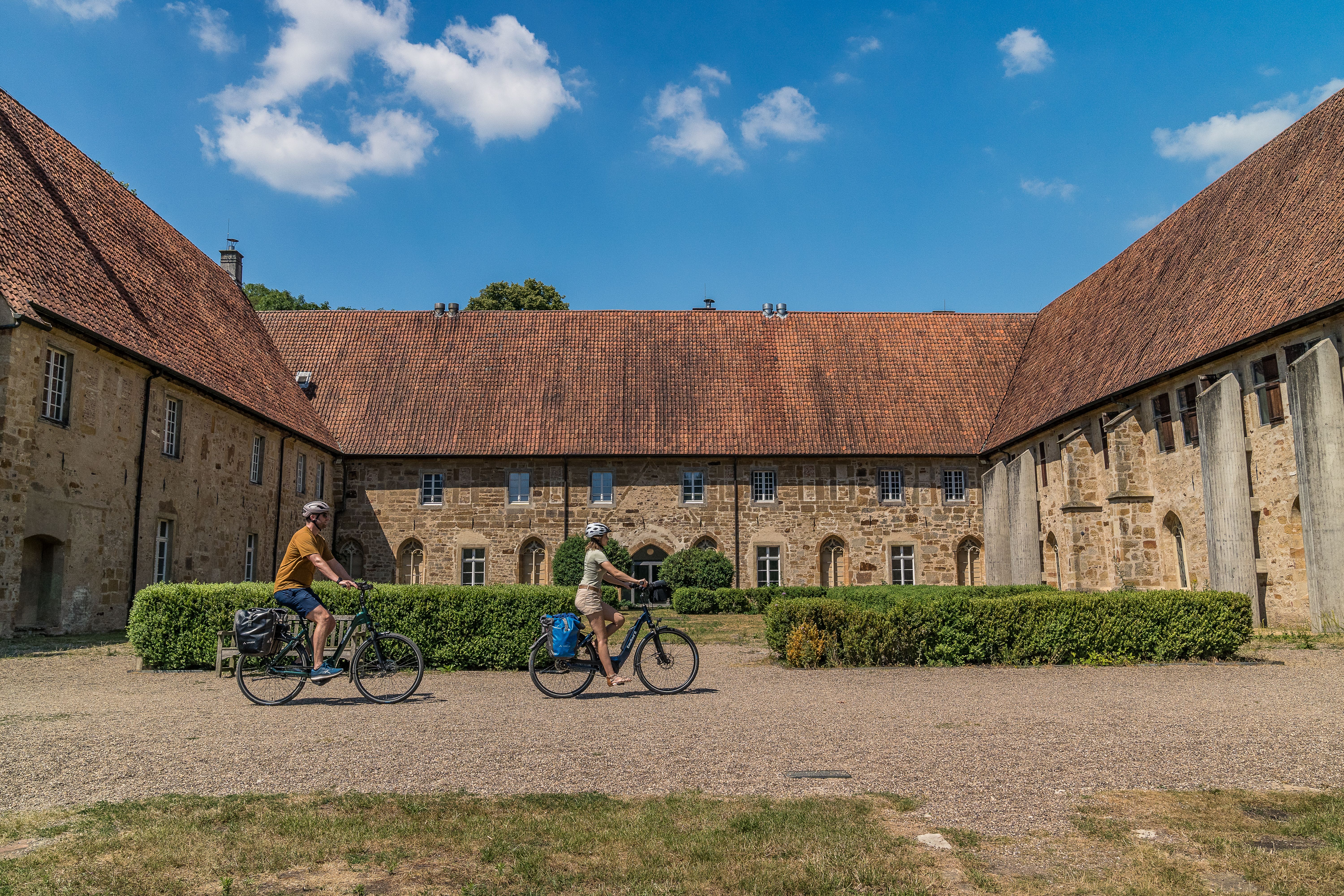 Mit dem Fahrrad durch den weitläufigen Innenhof des Klosters Bentlage: Die eindrucksvolle Klosteranlage verbindet Geschichte, Kultur und entspanntes Radfahren.